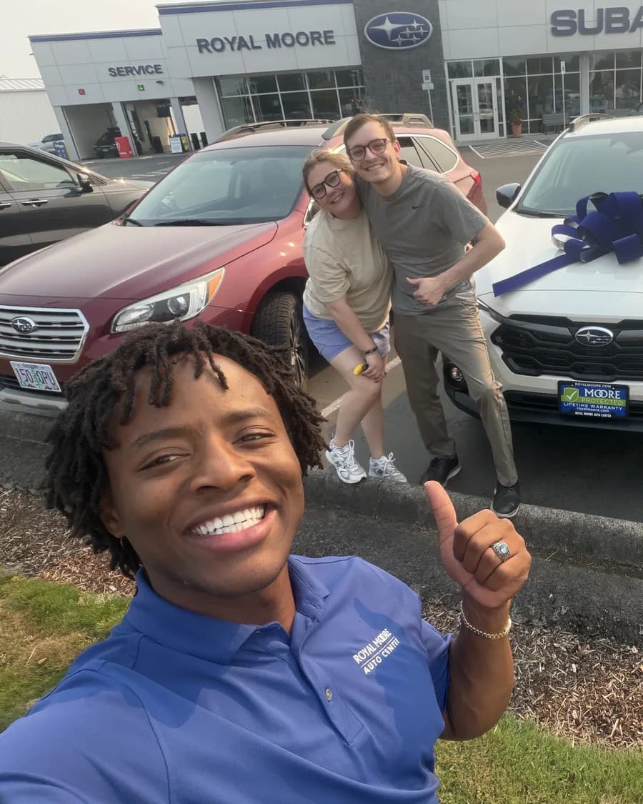 Artie Johnson with customers and their new white Subaru Crosstrek with a delivery bow