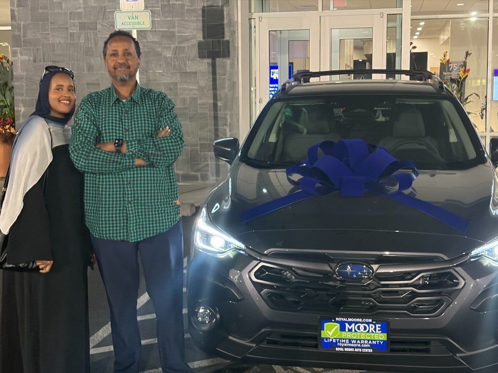 Customers with their Subaru Crosstrek at delivery, blue bow on the hood