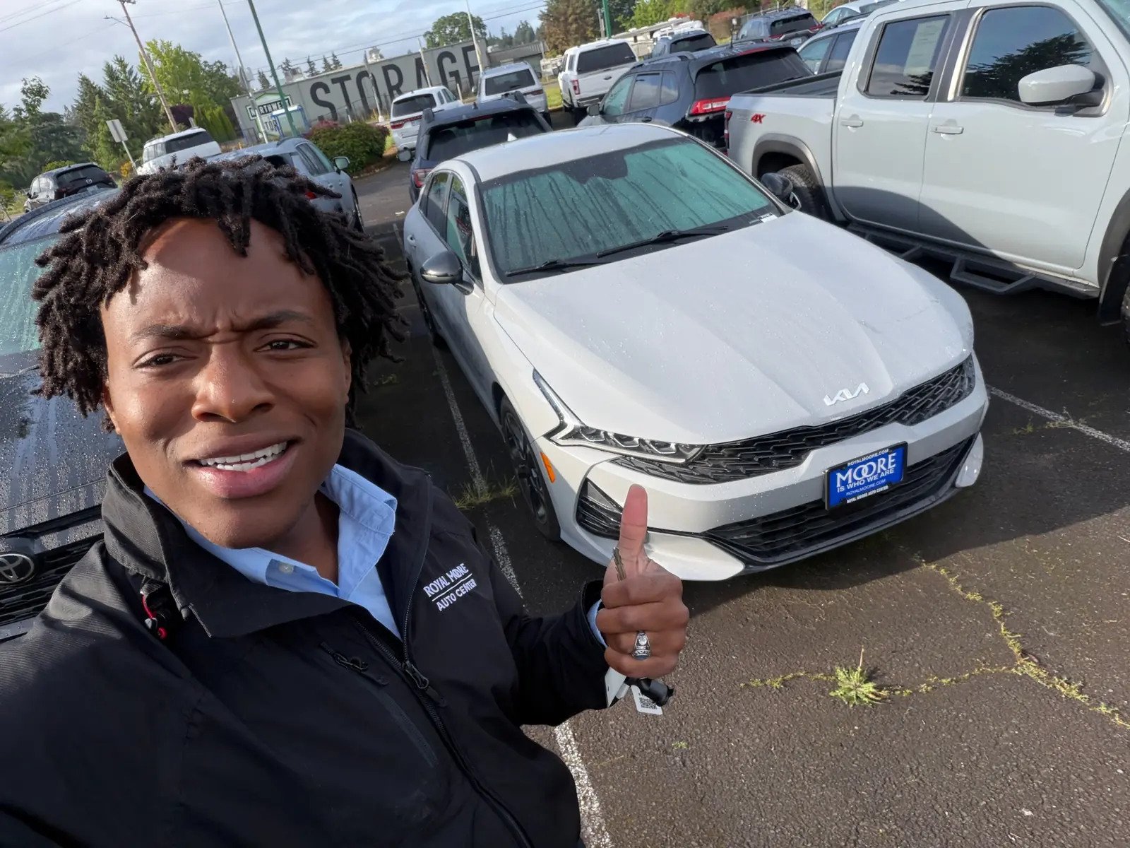 Artie beside a silver Kia on the dealership lot