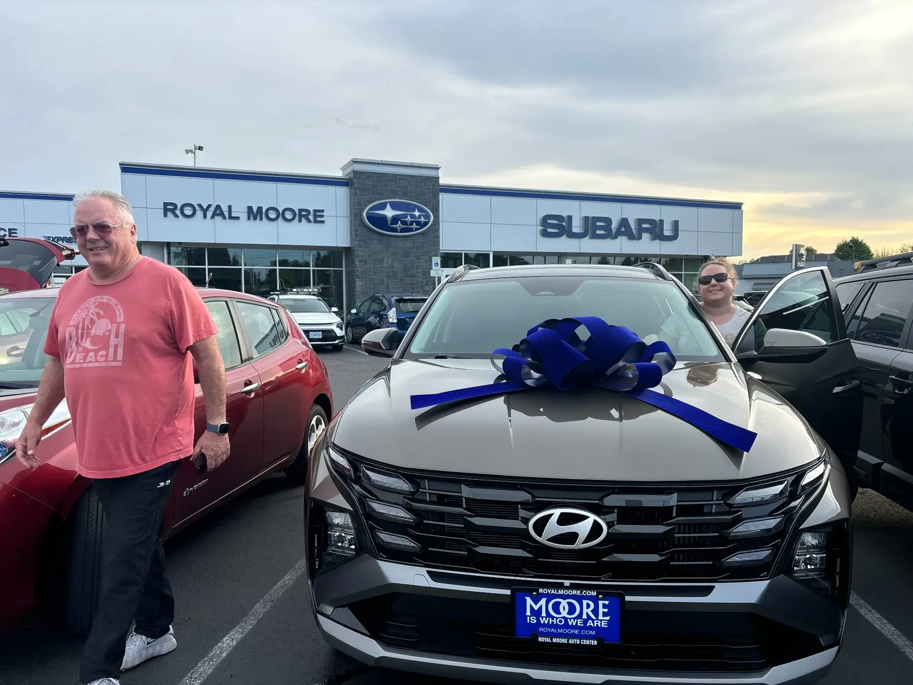 Customers beside a Hyundai with a blue delivery bow at Royal Moore
