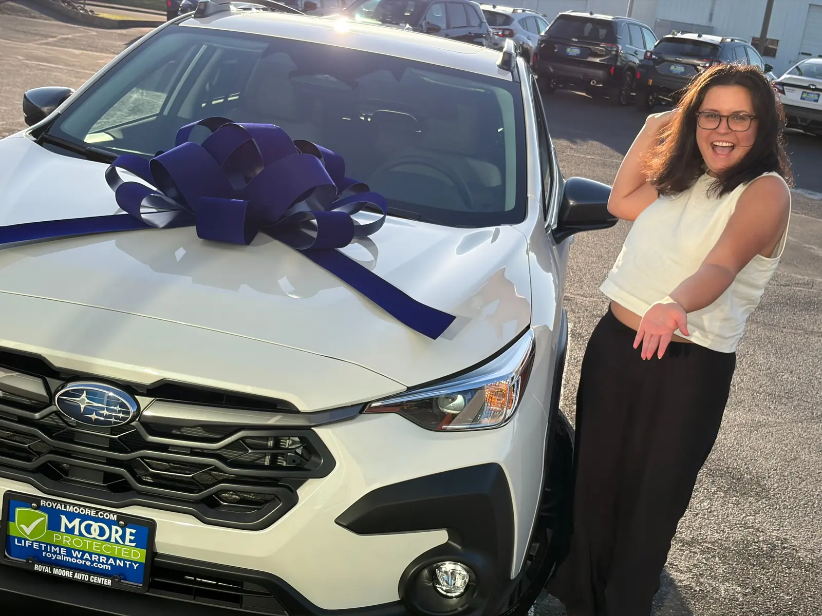 Customer celebrating beside a white Subaru with a blue delivery bow